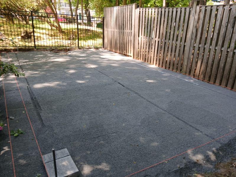 Finished dark paver patio bordered by a residential wood fence